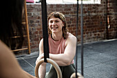 Smiling young woman exercising with friend in gym