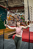Young female rock climber training at gymnastics rings