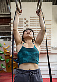 Female rock climber training at gymnastics rings