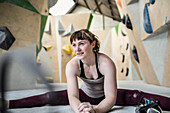 Young female rock climber stretching in climbing gym