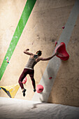 Female rock climber jumping from climbing wall
