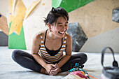 Happy female rock climber stretching in climbing gym