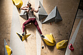 Female rock climber on climbing wall in gym