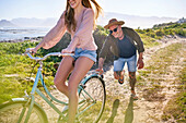 Happy boyfriend pushing girlfriend on bicycle