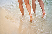Legs of couple running in ocean surf
