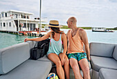 Couple relaxing on catamaran, looking at a houseboat