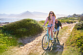 Carefree couple riding bicycle on sunny beach path