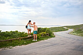 Couple standing on fence at ocean roadside