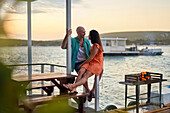 Happy couple relaxing and talking on houseboat patio on lake
