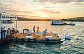 Carefree couple dancing on houseboat patio on lake at sunset