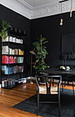Bücherregal im Zimmer mit schwarzen Wänden und Stuckdecke