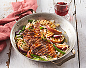 Grilled pork chops with apples in a pan
