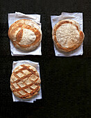 Three crusty breads on paper and dark base