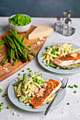 Pasta with green peas, asparagus and parmesan sauce, served with salmon fillet