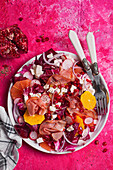 Radicchio salad with citrus fruits, pomegranate seeds, radishes, Parma ham, and feta cheese