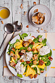 Spinach and rocket salad with mango, burrata, and garlic croutons