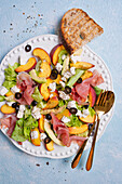 Lettuce with Parma ham, peach, olives, feta cheese, and avocado