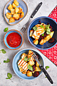 Spanish style dinner with baked potatoes, grilled halloumi, fried chorizo and ​​tomato sauce
