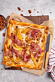 Puff pastry tart with ham, pears, pecan nuts, and onions