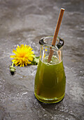 Dandelion juice, with a flower and bud on slate