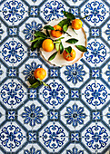 Clementines with leaves from Spain on a tiled surface