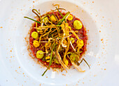 Beef Tartare with Saffron and Leek and Salted Almond on a white Plate