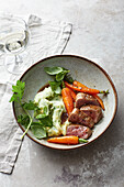 Roasted saddle of venison with mashed potatoes and herbs and caramelised carrots