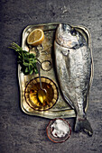Sea bream on a tray with marjoram, lemon and olive oil