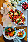 Mixed tomato salad with halloumi, burrata, fruits, and olives