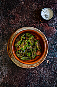 Roasted Padron peppers on a rusty metal background