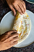 A Dosa being rolled (A dosa is a thin batter-based dish originating from South India, made from a fermented batter predominantly consisting of lentils and rice)