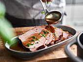Gravy being poured over smoked pork chops en cocotte