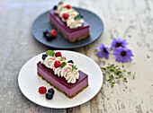 Vegan raspberry mousse tart with a pistachio base and blueberry glaze
