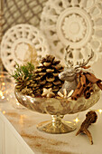 A bowl of golden pine cones, deer and cinnamon sticks as Christmas decoration