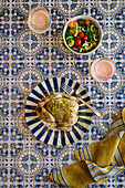 Fried Zaatar chicken served with a colourful vegetable salad on a tile background