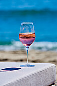 A glass of rosé wine on table by the sea