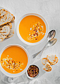 Creamy tomato soup with baguette and chilli flakes