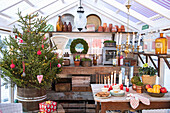 Christmas tree, wooden shelf with vintage decoration and table with candles in the greenhouse