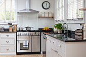 L-shaped kitchen with light cabinet fronts, window with blinds