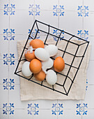 Fresh brown and white eggs with feathers in a basket