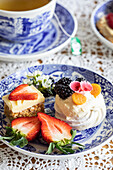 Meringue, fresh strawberries, and a slice of cake on a blue and white plate