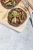 Black crust pizza with root vegetables, apple, and rocket