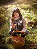 Mädchen prüft Pilz beim Pilze sammeln im Wald