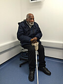Elderly man sitting down in a hospital waiting room