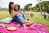 Happy mum and disabled daughter enjoying picnic on blanket
