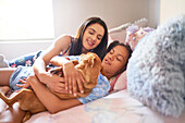 Mother and daughter laying in bed with dog at home