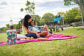 Mum and disabled daughter using tablet on picnic blanket