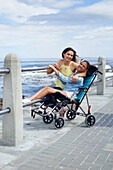 Happy mother and disabled daughter in pushchair at beach
