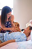 Mother, disabled daughter and dog cuddling on bed at home