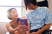 Mother and daughter in wheelchair looking at smart phone